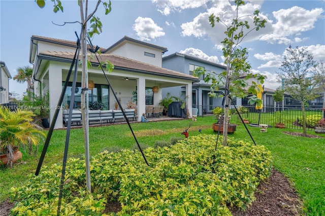 back of property with a patio area, ceiling fan, fence, and a yard