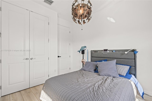 bedroom with light wood-style flooring, a closet, and visible vents