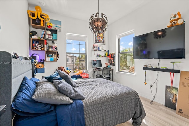 bedroom with a notable chandelier, baseboards, and wood finished floors