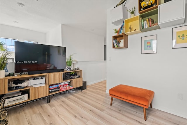 living area with baseboards and wood finished floors