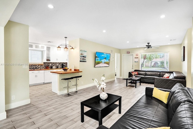 living area featuring a ceiling fan, recessed lighting, light wood-style flooring, and baseboards