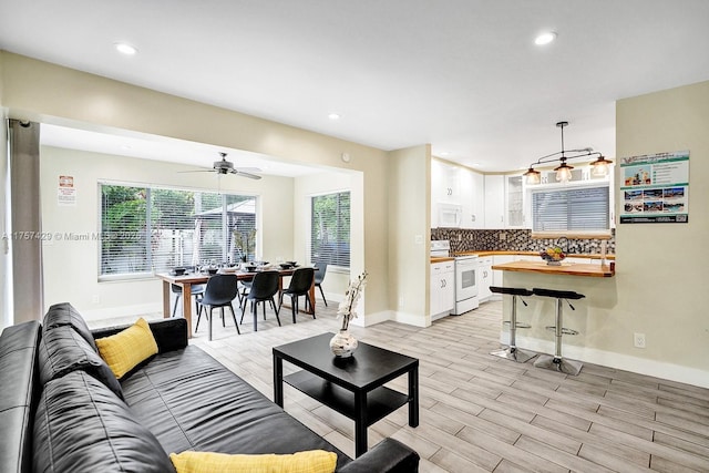 living area featuring baseboards, light wood-style flooring, and recessed lighting