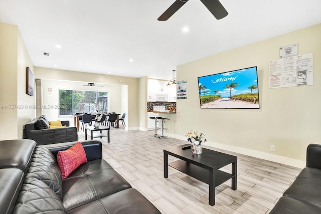 living room with recessed lighting, visible vents, baseboards, and wood finish floors