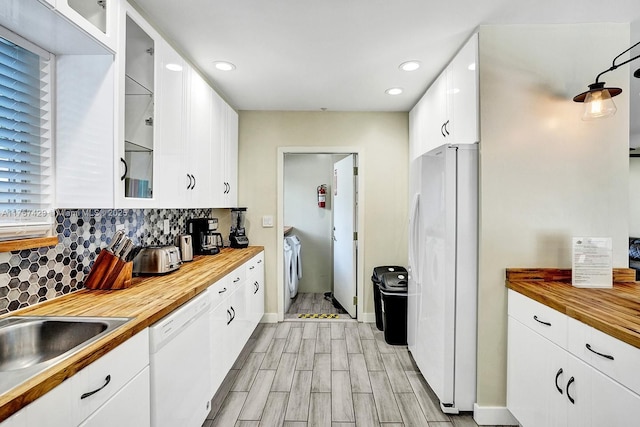 kitchen featuring butcher block countertops, washer and dryer, white appliances, and white cabinets