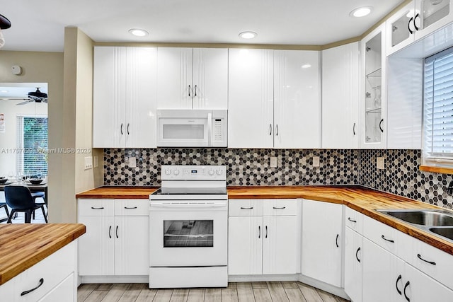 kitchen with white appliances, butcher block countertops, and white cabinetry