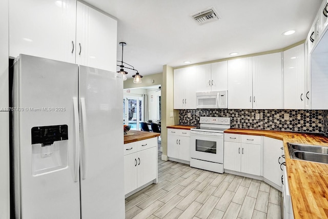 kitchen with tasteful backsplash, visible vents, wooden counters, white cabinetry, and white appliances