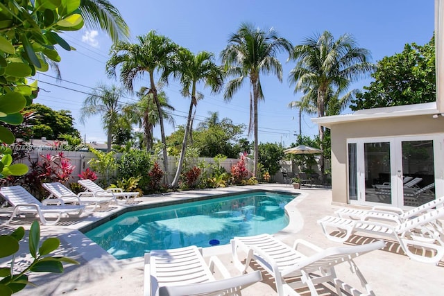 view of swimming pool featuring a fenced backyard, french doors, a fenced in pool, and a patio