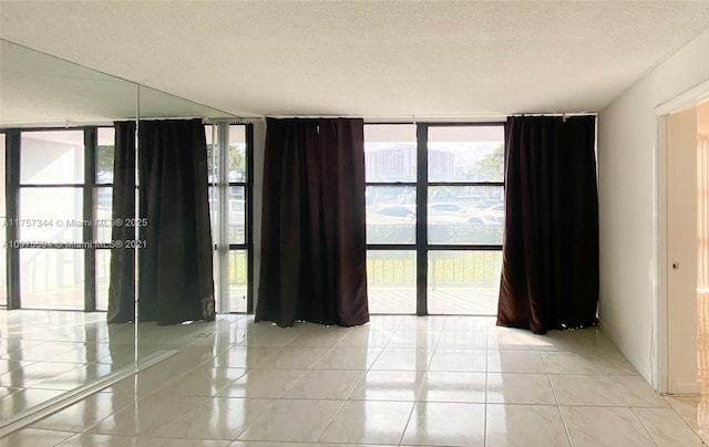 empty room featuring expansive windows, a textured ceiling, and light tile patterned flooring