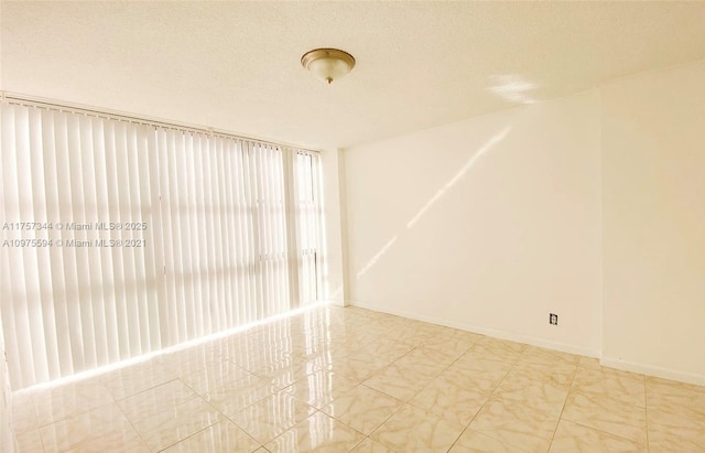 unfurnished room with a textured ceiling and baseboards