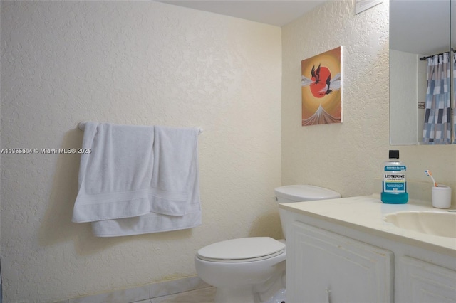 full bathroom with toilet, tile patterned flooring, vanity, and a textured wall