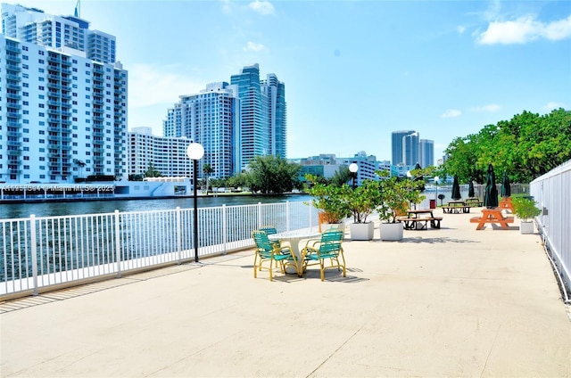 view of patio with a city view, a water view, and fence