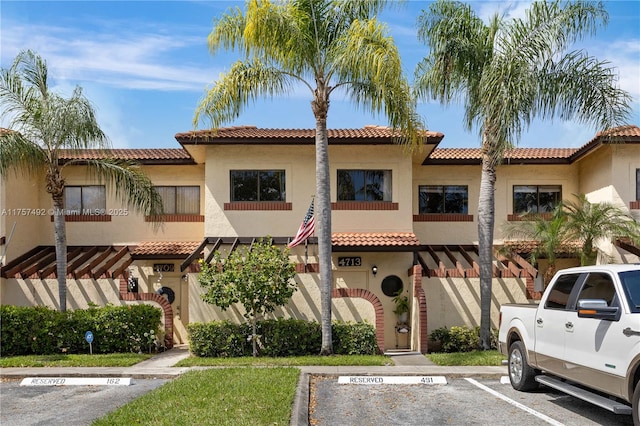 mediterranean / spanish home with uncovered parking and stucco siding