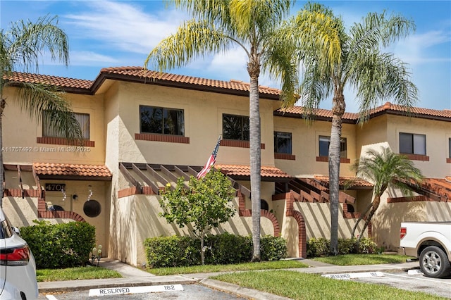 mediterranean / spanish-style house with uncovered parking, a tiled roof, and stucco siding