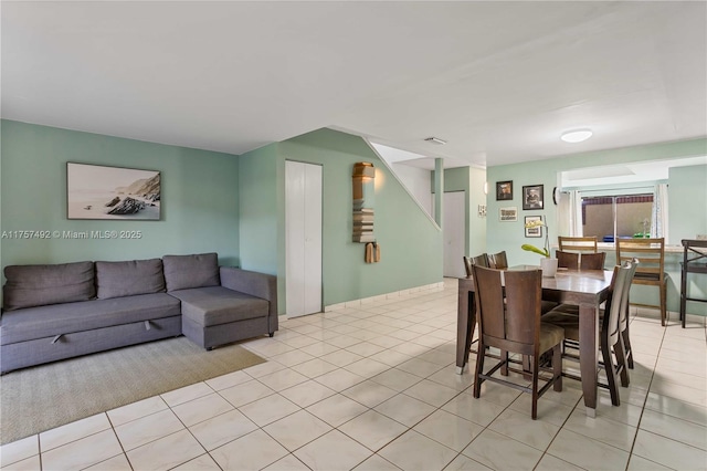 dining area featuring light tile patterned floors, stairway, and visible vents