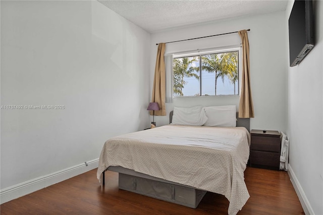 bedroom with a textured ceiling, baseboards, and wood finished floors