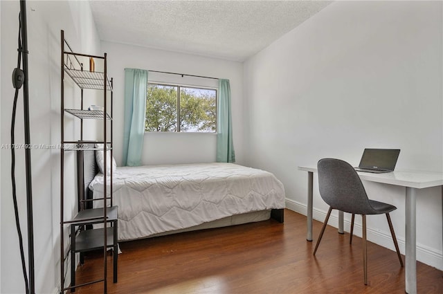 bedroom with a textured ceiling, baseboards, and wood finished floors