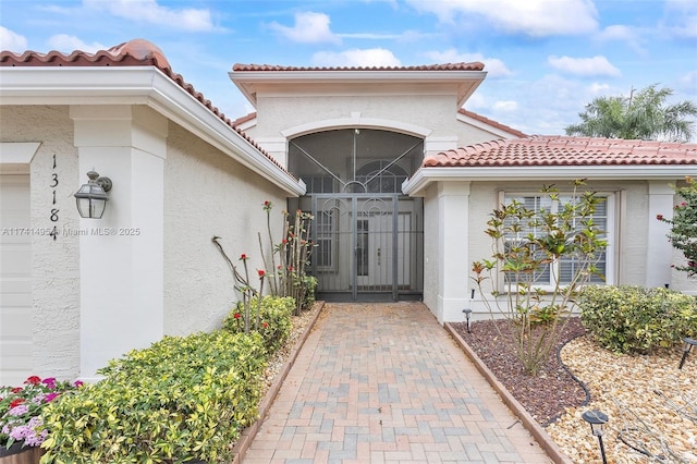 doorway to property with a gate, a tiled roof, and stucco siding