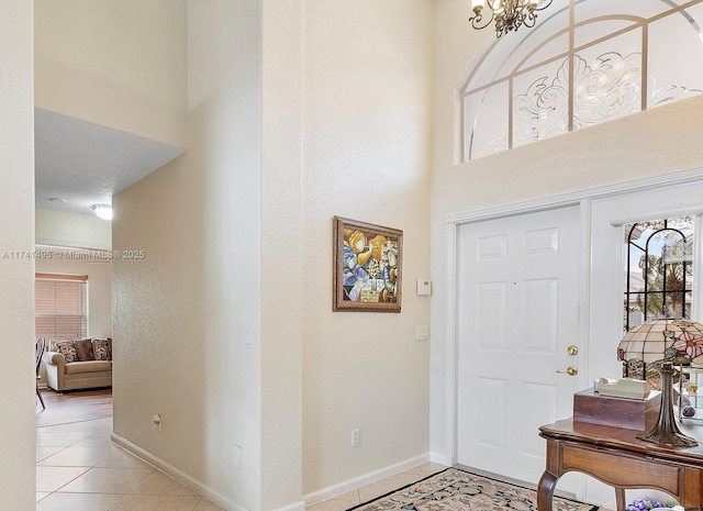 foyer entrance with a high ceiling, light tile patterned flooring, and baseboards