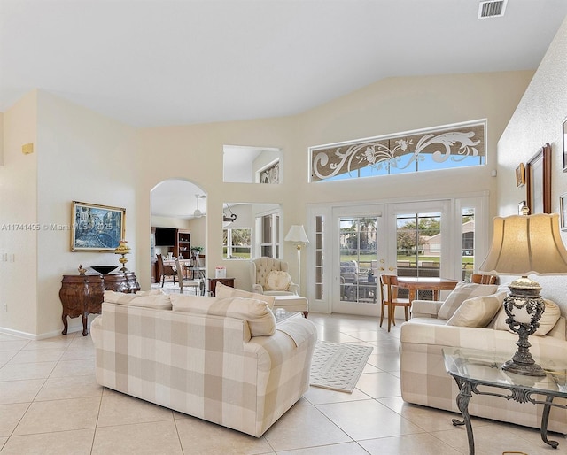 living room with light tile patterned floors, arched walkways, high vaulted ceiling, and french doors