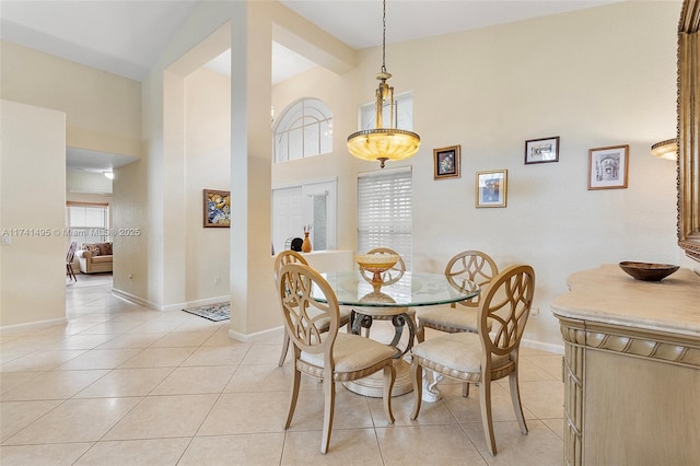 dining space featuring light tile patterned floors, baseboards, and high vaulted ceiling