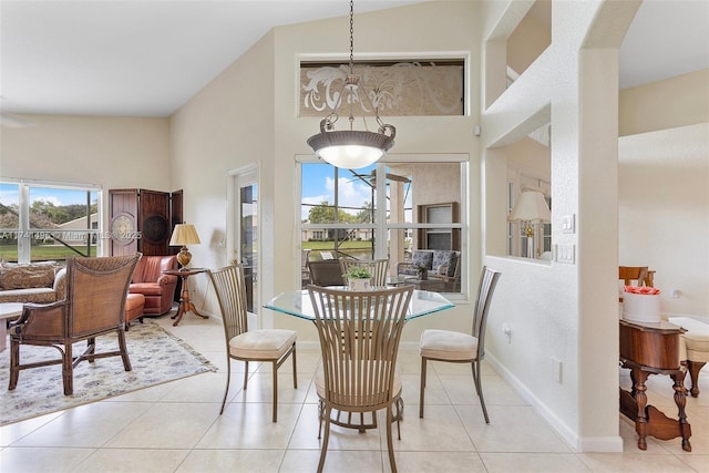 dining room featuring light tile patterned floors, a towering ceiling, and baseboards