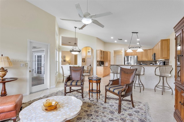 living room featuring light tile patterned floors, ceiling fan, vaulted ceiling, and arched walkways