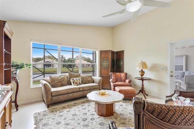 living area featuring ceiling fan, light tile patterned flooring, and baseboards