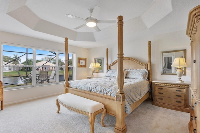 bedroom with a tray ceiling, light carpet, ceiling fan, and baseboards