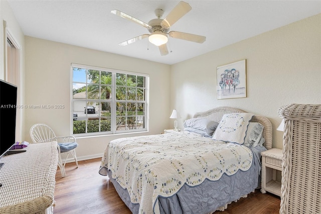 bedroom with wood finished floors, a ceiling fan, and baseboards