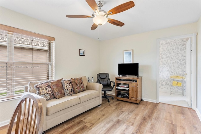 living room featuring baseboards, ceiling fan, and light wood finished floors