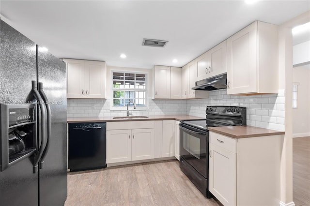 kitchen with light wood-type flooring, a sink, under cabinet range hood, and black appliances