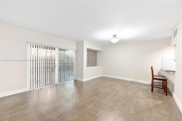 unfurnished room with visible vents, baseboards, and wood finished floors