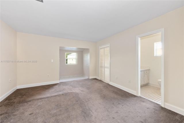 unfurnished room featuring carpet and baseboards