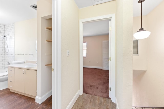 bathroom with toilet, wood finished floors, vanity, visible vents, and baseboards