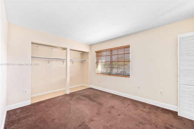 unfurnished bedroom featuring carpet floors, baseboards, and two closets