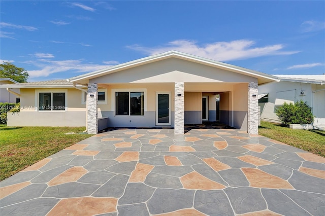 rear view of property featuring a yard, a patio, and stucco siding