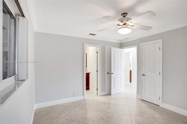 empty room with light tile patterned flooring, ceiling fan, visible vents, and ornamental molding