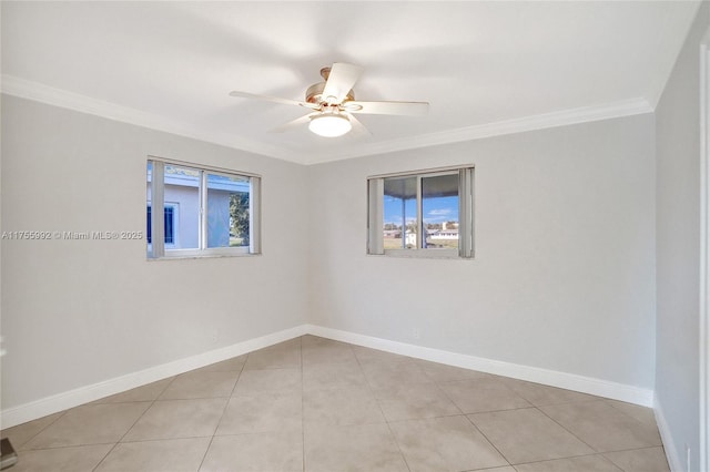 spare room with ornamental molding, light tile patterned floors, baseboards, and a ceiling fan