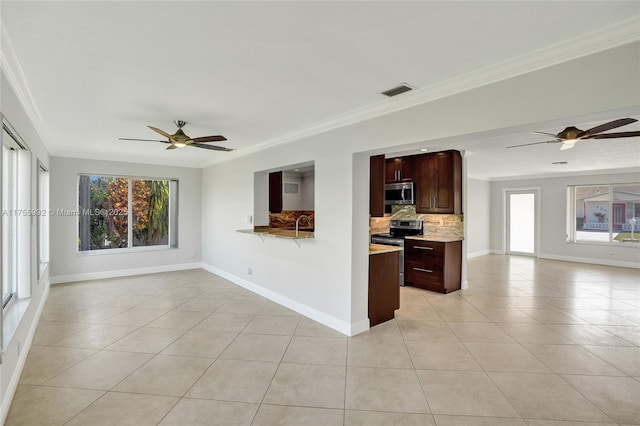 kitchen featuring open floor plan, appliances with stainless steel finishes, a healthy amount of sunlight, and crown molding