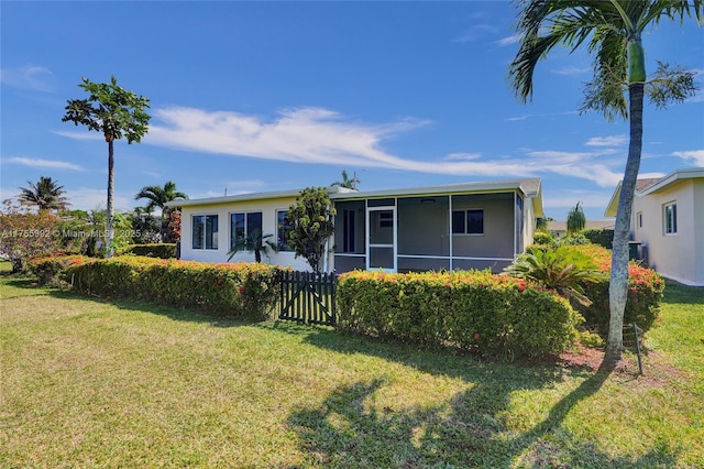 view of front of house featuring a front yard, fence, and a sunroom