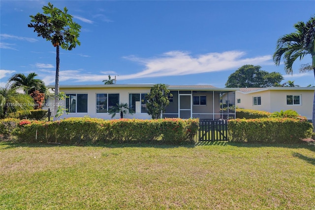 back of property with a sunroom, a lawn, and stucco siding