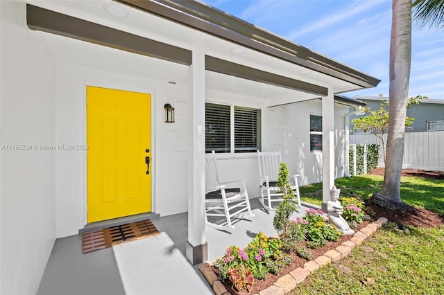 property entrance with covered porch and fence