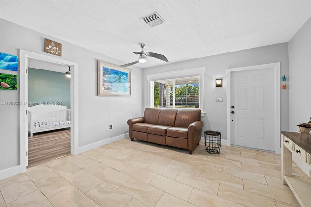 living area with a ceiling fan, visible vents, and baseboards