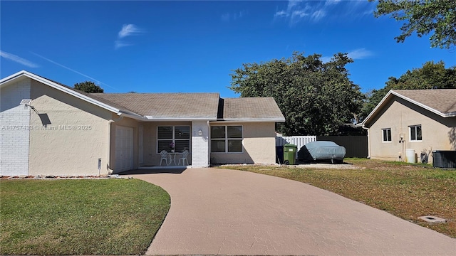 view of front of home with a front yard, fence, central AC unit, concrete driveway, and a garage