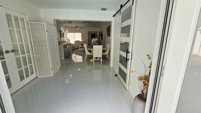 hall featuring tile patterned flooring, french doors, and a barn door