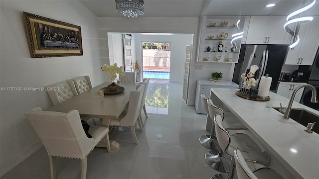 kitchen with open shelves, freestanding refrigerator, a sink, light countertops, and white cabinetry