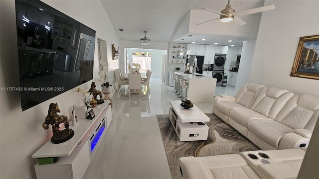 living room featuring visible vents, stacked washer and clothes dryer, a ceiling fan, and vaulted ceiling