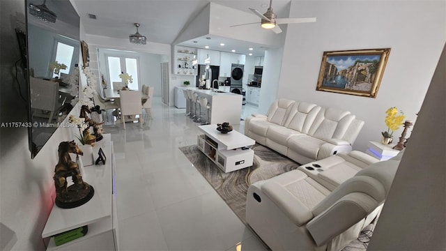 living area featuring light tile patterned floors, visible vents, stacked washer and dryer, and ceiling fan