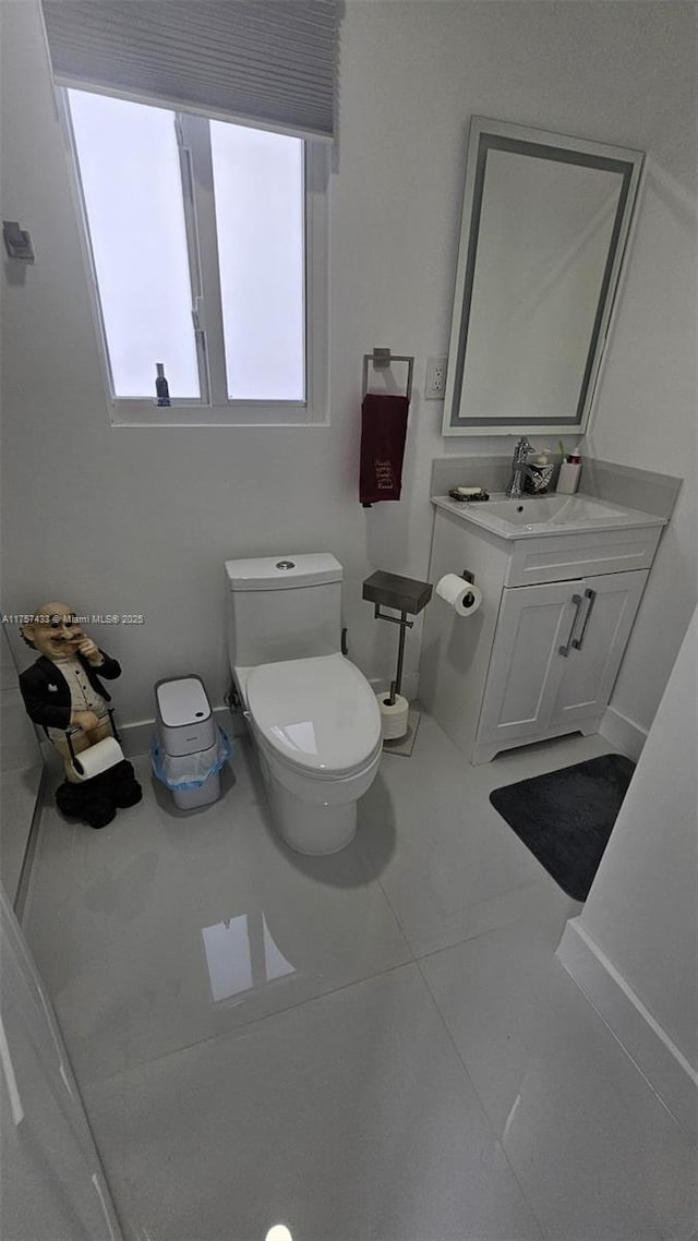 half bath featuring tile patterned flooring, toilet, and vanity