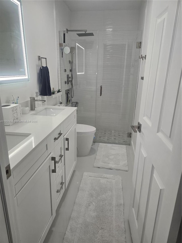 full bathroom featuring double vanity, a stall shower, toilet, and a sink